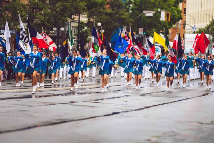 A vibrant marching band parades through the streets of Victoria, BC, showcasing flags and uniforms.