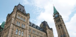 A view of the historical Parliament Hill building in Ottawa against a clear sky.