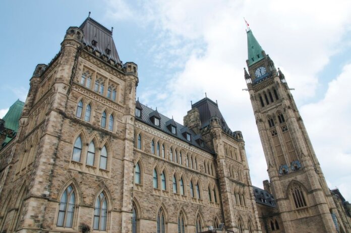 A view of the historical Parliament Hill building in Ottawa against a clear sky. A view of the historical Parliament Hill building in Ottawa against a clear sky.