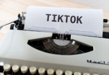 A vintage typewriter holding paper with TikTok written, symbolizing modern social media trends.