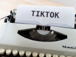 A vintage typewriter holding paper with TikTok written, symbolizing modern social media trends.