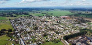 Консерваторы представили «Большой план для малых городов» Канады Aerial photo of a rural town surrounded by green fields under a cloudy sky, showcasing its layout.