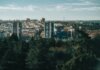 Aerial view of a city with high-rise buildings and lush trees in the foreground.