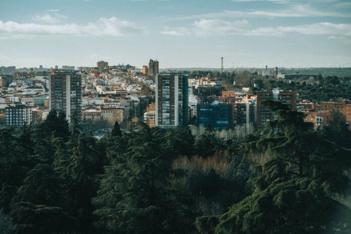 Aerial view of a city with high-rise buildings and lush trees in the foreground.