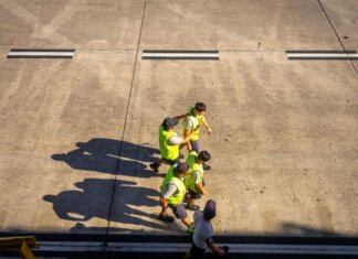 Aerial view of airport workers walking on the tarmac in Buenos Aires on a sunny day.
