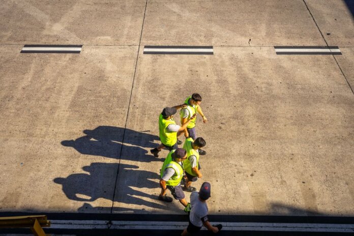 Aerial view of airport workers walking on the tarmac in Buenos Aires on a sunny day. Aerial view of airport workers walking on the tarmac in Buenos Aires on a sunny day.