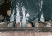 BC Hydro покупает Island Generation для надёжности энергоснабжения Aerial view of cascading water over a concrete dam showcasing turbulent flow and water management.