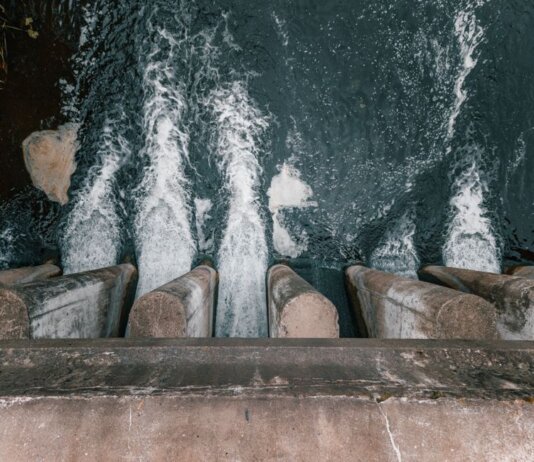 Aerial view of cascading water over a concrete dam showcasing turbulent flow and water management.