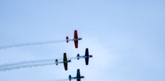 Aerobatic planes performing a synchronized airshow against a clear Lisbon sky. Captivating flight maneuvers.