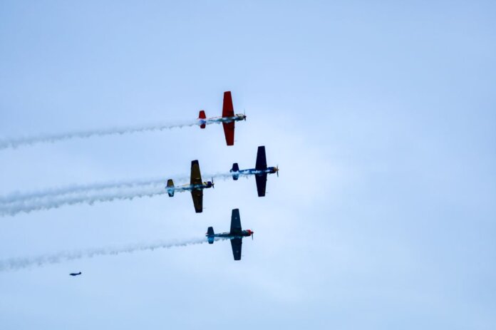 Aerobatic planes performing a synchronized airshow against a clear Lisbon sky. Captivating flight maneuvers.