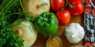 An assortment of fresh vegetables and spices on a wooden table for healthy cooking.