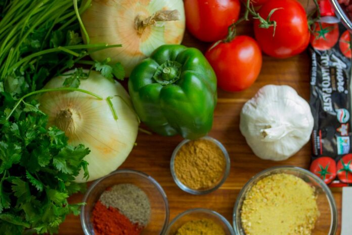 An assortment of fresh vegetables and spices on a wooden table for healthy cooking. An assortment of fresh vegetables and spices on a wooden table for healthy cooking.