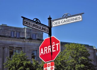 Канада подписала Конвенцию ООН о киберпреступности Bilingual street signs with stop sign against a clear blue sky in a city setting, featuring historical street names.