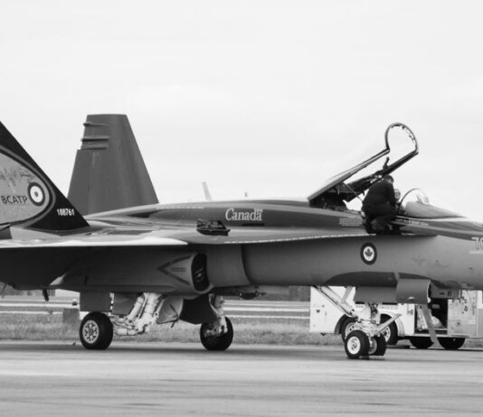 Canadian fighter jet on airstrip. Monochrome image showcasing aviation and military theme.