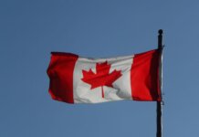 Canadian flag prominently displayed against a clear blue sky, symbolizing national pride.