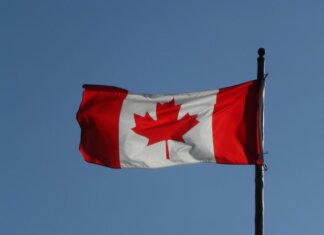 Canadian flag prominently displayed against a clear blue sky, symbolizing national pride.