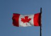 Canadian flag prominently displayed against a clear blue sky, symbolizing national pride.