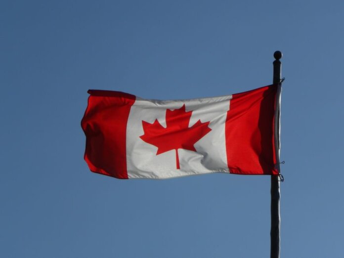 Canadian flag prominently displayed against a clear blue sky, symbolizing national pride.