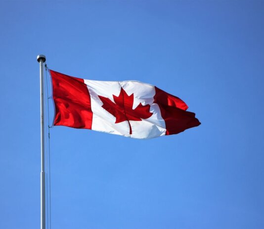 Canadian flag waving proudly against a clear blue sky in Victoria, BC.