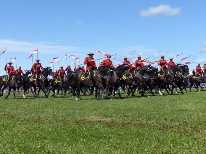 Canadian Mounties in red uniforms riding horses at an outdoor event. Canadian Mounties in red uniforms riding horses at an outdoor event.