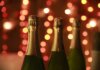 Министры Канады объявят о мерах в ответ на американские пошлины Champagne bottles in a warm festive setting with sparkling bokeh lights for celebration.