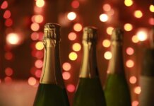 Министры Канады объявят о мерах в ответ на американские пошлины Champagne bottles in a warm festive setting with sparkling bokeh lights for celebration.
