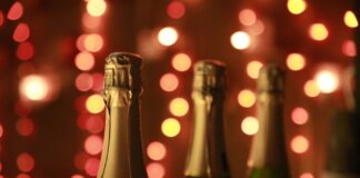 Champagne bottles in a warm festive setting with sparkling bokeh lights for celebration.
