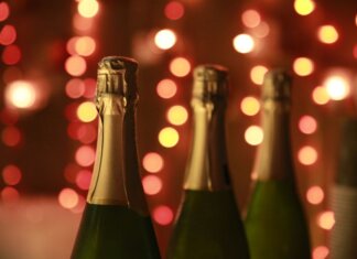 Champagne bottles in a warm festive setting with sparkling bokeh lights for celebration.