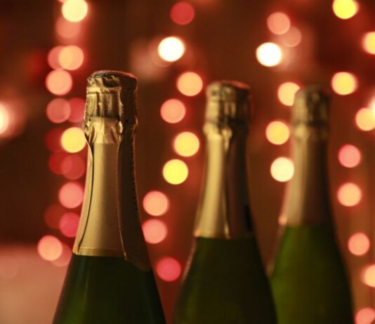 Champagne bottles in a warm festive setting with sparkling bokeh lights for celebration.