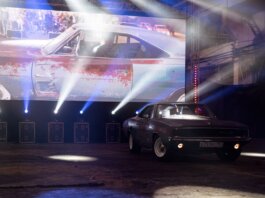 Classic muscle car illuminated by stage lights in a nostalgic indoor venue.