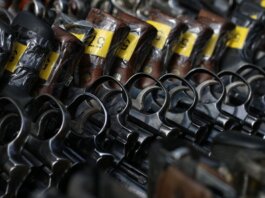 Close-up image of revolvers with yellow tags arranged on a rack.