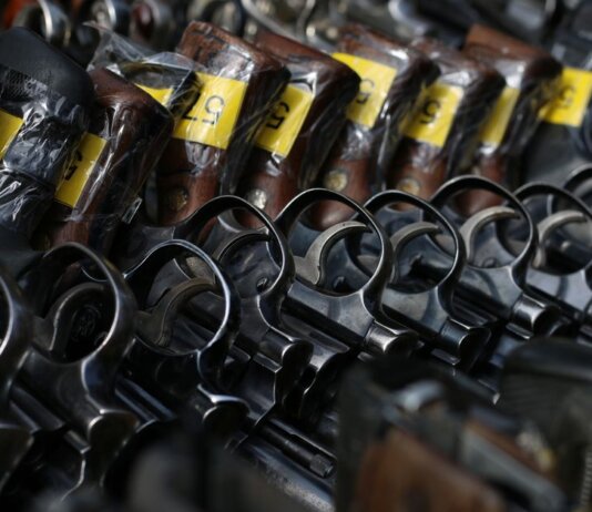 Close-up image of revolvers with yellow tags arranged on a rack.