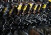 Close-up image of revolvers with yellow tags arranged on a rack.