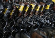 Close-up image of revolvers with yellow tags arranged on a rack.