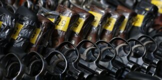 Close-up image of revolvers with yellow tags arranged on a rack.