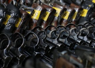 Close-up image of revolvers with yellow tags arranged on a rack.