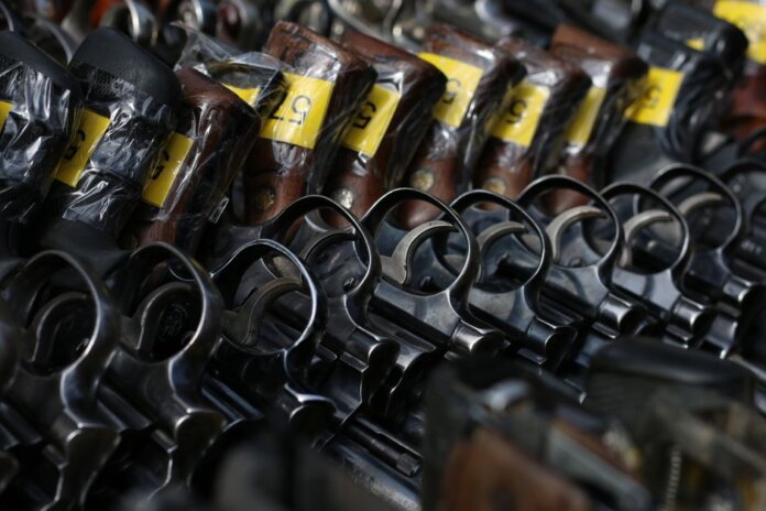 Close-up image of revolvers with yellow tags arranged on a rack.