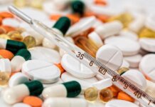 Close-up image showing various pills and a thermometer, emphasizing health and medicine.