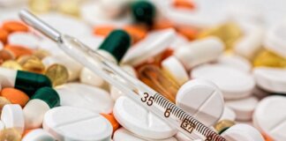 Close-up image showing various pills and a thermometer, emphasizing health and medicine.