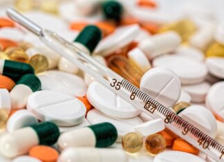 Close-up image showing various pills and a thermometer, emphasizing health and medicine.