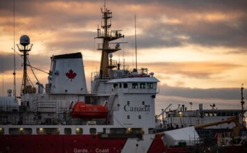 Close-up of a Canadian Coast Guard ship docked at sunset, showcasing maritime details.