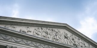 Консерваторы требуют отменить директиву, ущемляющую французский в армии Close-up of a classical architectural pediment with detailed sculptures and columns.