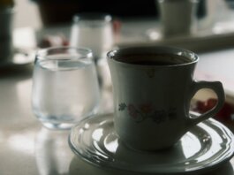 Close-up of a floral coffee cup and water glass on a table setting.