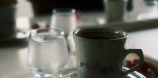 Close-up of a floral coffee cup and water glass on a table setting.