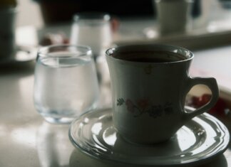 Close-up of a floral coffee cup and water glass on a table setting.