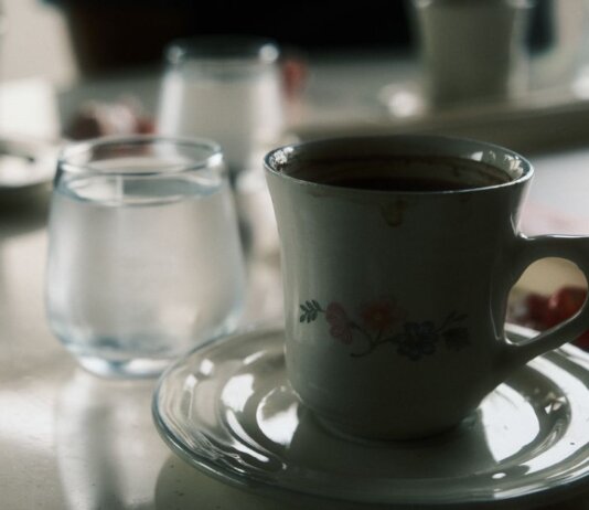 Close-up of a floral coffee cup and water glass on a table setting.