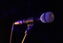Министр Миллер приветствует участие Канады в «Евровидении» Close-up of a microphone set up on stage, highlighting concert ambiance.