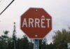 Close-up of a red French stop sign outdoors with trees in the background.