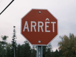 Close-up of a red French stop sign outdoors with trees in the background.