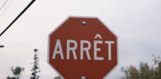 Close-up of a red French stop sign outdoors with trees in the background.